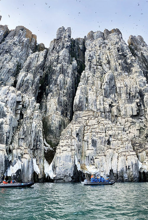 Guests on the National Geographic Endurance cruise at the cliffs of Alkefjellet in Svalbard.