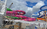 The waterslides in the Thrill Island waterpark on Icon of the Seas: raft slides to the left, single-rider slides to the right.